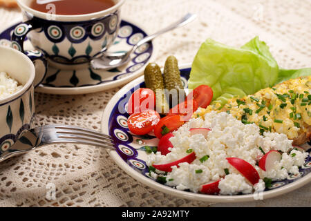 Sana colazione con pane e formaggio bianco, uova strapazzate e pomodori Foto Stock