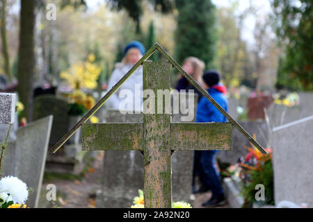 Vecchia croce di legno in un cimitero e la famiglia in background per la festa del giorno di tutti i santi al 1 Novembre e spazio vuoto per il testo Foto Stock