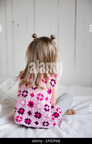 Ragazza seduta sul letto Foto Stock