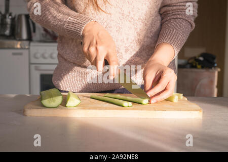 Donna taglio di cetriolo in cucina Foto Stock