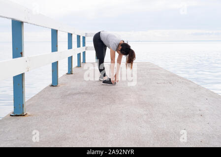 La donna si allunga a jetty Foto Stock