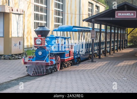 Hodenhagen, Germania, 30 marzo 2019: bambini in ferroviaria zoo, una locomotiva a vapore e auto blu in piedi alla stazione presso la piattaforma Foto Stock