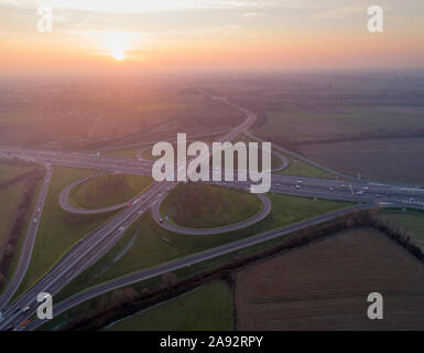 Interscambio quadrifoglio visto da sopra. Vista aerea dell'autostrada bivio nella pianura padana vicino a Milano al tramonto. Colpo d'occhio. Foto Stock