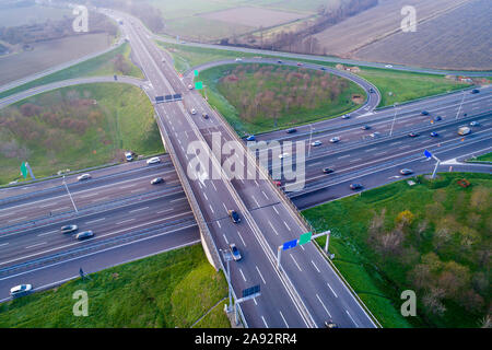 Interscambio quadrifoglio visto da sopra. Vista aerea dell'autostrada bivio nella pianura padana vicino a Milano al tramonto. Colpo d'occhio. Foto Stock