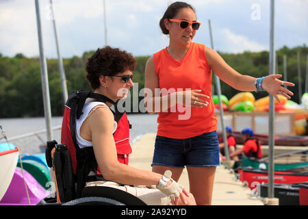 Donna con una lesione del midollo spinale che parla con un istruttore su come usare un kayak Foto Stock