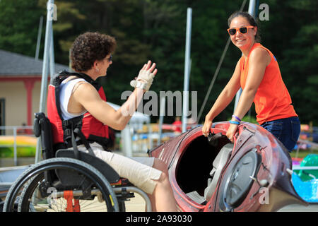 Donna con una lesione del midollo spinale che parla con un istruttore su come usare un kayak Foto Stock