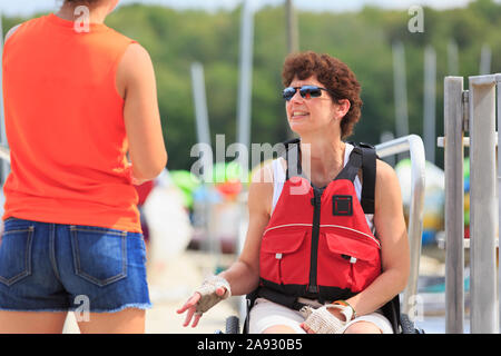 Donna con una lesione del midollo spinale che parla con un istruttore su come usare un kayak Foto Stock