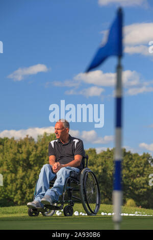 Uomo con lesione del midollo spinale in una sedia a rotelle in attesa di giocare a golf Foto Stock