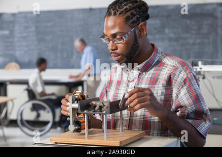 Studente che ha avuto meningite spinale e ha problemi uditivi che funzionano su un esperimento di elettromagnetismo in laboratorio Foto Stock