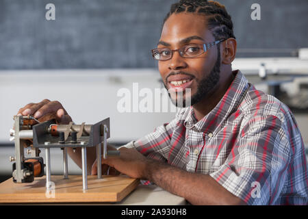 Studente che ha avuto meningite spinale e con compromissione dell'udito funzionante su un esperimento di elettromagnetismo in laboratorio Foto Stock