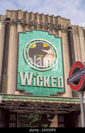 Vista di Apollo Victoria Theatre London (di fronte alla stazione di Victoria) pubblicità hit musical produzione malvagi. La metropolitana di Londra roundel in primo piano. Foto Stock