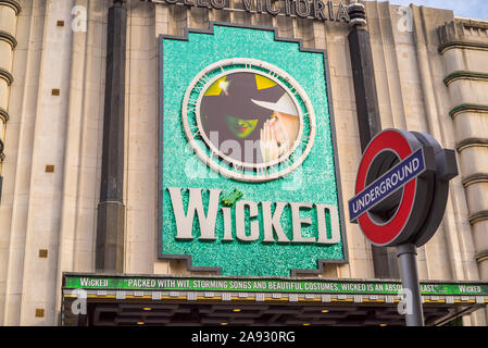 Vista di Apollo Victoria Theatre London (di fronte alla stazione di Victoria) pubblicità hit musical produzione malvagi. La metropolitana di Londra roundel in primo piano. Foto Stock