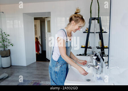 Donna sorridente lavaggio delle mani Foto Stock