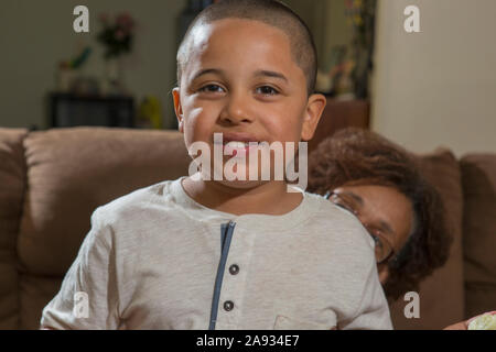 Ragazzo ispanico con autismo seduto con la nonna a casa Foto Stock