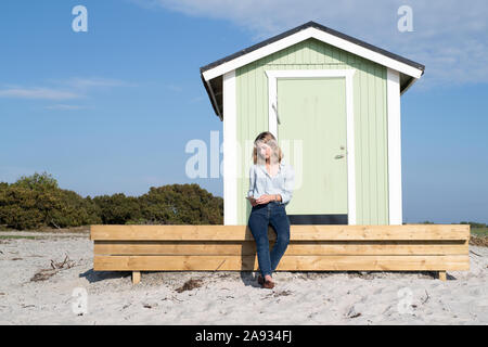 Donna di fronte beach hut Foto Stock