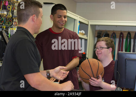 Giovane uomo con la sindrome di Down che consegna il basket al suo amici al dispensario di attrezzature universitarie per la palestra Foto Stock