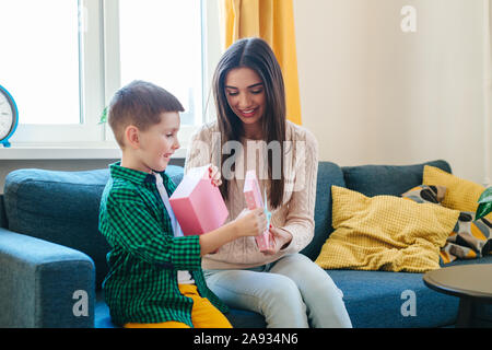 Felice Festa della mamma. Carino piccolo ragazzo si congratula con la madre e dà una scatola presente Foto Stock