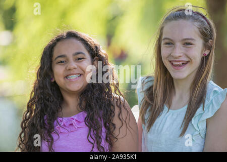 Ritratto di due teen suore ispaniche con bretelle sorridenti un parco Foto Stock