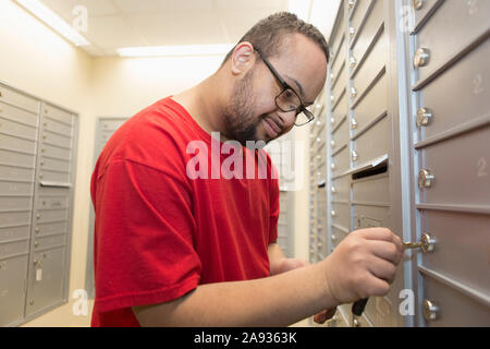 L'uomo afroamericano con la sindrome di Down che controlla la sua casella postale Foto Stock