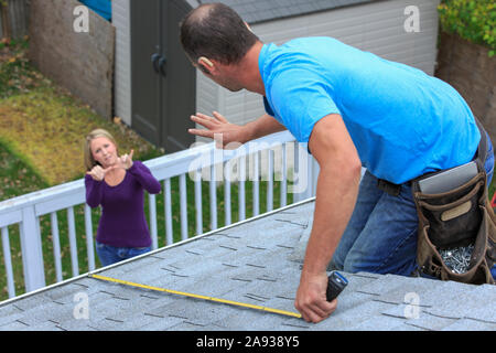 Homeowner e roofer comunicare in lingua americana dei segni circa 'Measure' e '4 piedi' Foto Stock