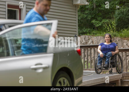Donna con spina Bifida e suo marito che si prepara a. salire in auto Foto Stock
