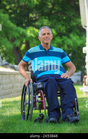 Ritratto di uomo felice con una ferita del midollo spinale dentro sedia a rotelle sul prato Foto Stock