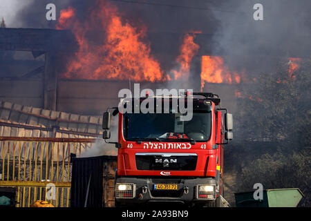 Israele. 12 Nov 2019. Vigili del fuoco israeliano di mettere fuori fuoco in una fabbrica di masterizzazione colpita da razzi lanciati dalla Striscia di Gaza nel sud della città israeliana di Sderot, nov. 12, 2019. Alcuni 50 razzi sono stati sparati martedì mattina in corrispondenza del centro e del sud di Israele, ferendo almeno una persona in una ritorsione palestinese dopo che Israele ha ucciso un senior Jihad islamica comandante in Gaza. (JINI via Xinhua) Credito: Xinhua/Alamy Live News Foto Stock