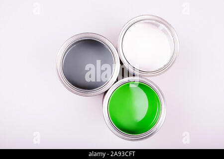 Spazzola di vernice ans top di lattine riempite con verde bianco e vernice grigio Foto Stock