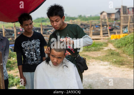 L'uomo avente il suo taglio di capelli in un mercato aperto vicino al Phaung Daw Pagoda u. Lago Inle MYANMAR Birmania Foto Stock