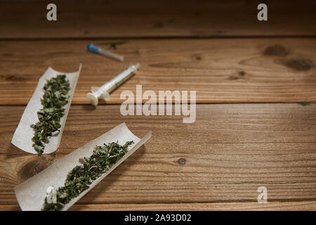 Il concetto di droga. le siringhe e i fumatori weed su una superficie in legno con spazio per testo orizzontale. shot. Foto Stock