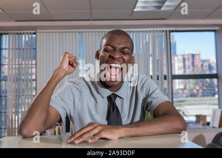 Felice uomo afroamericano con autismo che acclamano in un ufficio Foto Stock