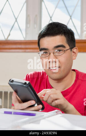 Ritratto dell'uomo asiatico con autismo che lavora sulla sua cella telefono Foto Stock