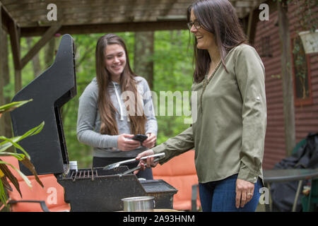 Donna con sclerosi multipla cucinare all'aperto con sua figlia Foto Stock