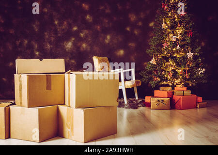 In Movimento per la casa nuova per il concetto di Natale. Focus sulla delocalizzazione di cartone scatole e albero di Natale decorato con presenta sotto di esso sullo sfondo Foto Stock