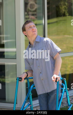 Giovane uomo con paralisi cerebrale usando il suo camminatore per camminare al lavoro Foto Stock