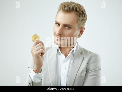 Ritratto di una bella bionda modello da uomo in modo completo grigio contiene un Bitcoin isolati su sfondo bianco in studio Foto Stock