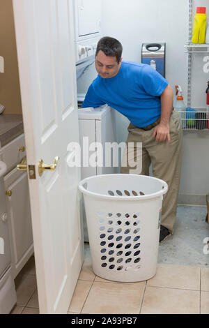 Uomo con sindrome di Down togliendo i vestiti asciutti dal lavaggio macchina Foto Stock