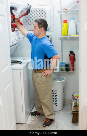 Uomo con sindrome Down in piedi in lavanderia Foto Stock