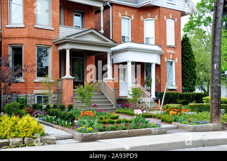 Questa bella, urban cortile anteriore Garden dispone di una grande veranda, mattone lastricatore passerella, parete di ritegno con impianti di bulbi, arbusti e piante perenni. Foto Stock