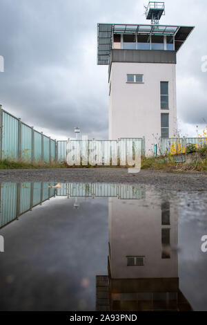 Marienborn, Germania. 09Nov, 2019. Il comandante la torre del ex fortezza di frontiera Marienborn è riflessa in una pozza di pioggia. Fino alla caduta del muro di Berlino, la più grande valico di frontiera sul confine interno-tedesco è stato collocato su questo sito. Oggi il memoriale della divisione tedesca Marienborn si trova lì. Credito: Klaus-Dietmar Gabbert/dpa-Zentralbild/ZB/dpa/Alamy Live News Foto Stock