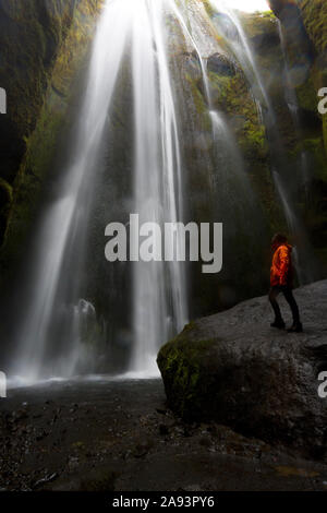 Escursionista guarda al potere della cascata Gljufrabui cascading in una gola nascosta vicino al popolare attration turistica. Seljalandsfoss cascata nel sud dell'Islanda Foto Stock