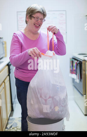 Donna con autismo gettando spazzatura in bidone Foto Stock