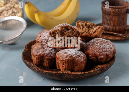 Muffin alla banana con fiocchi di avena spolverati con zucchero a velo su una piastra di noce di cocco, orientamento orizzontale Foto Stock