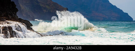 Le onde tropicali dell'oceano si infrangono e si spruzzi, Na Pali Coast; Kauai, Hawaii, Stati Uniti d'America Foto Stock