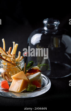 Formaggi assortiti con frutti di bosco e confettura, mini servire in un pallone di vetro. Cucina di fusione concetto chiave di basso, spazio di copia Foto Stock