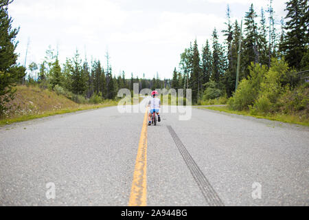 Vista posteriore del giovane ragazzo in mountain bike sulla bilancia bike. Foto Stock