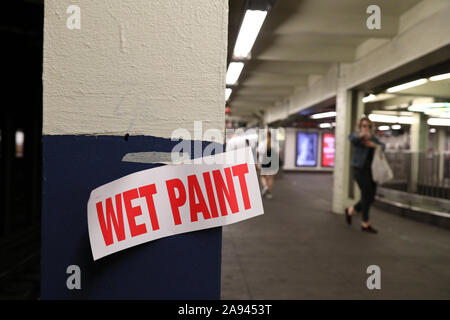 Un umido segno di vernice di viaggio legato a una colonna della piattaforma in una New York alla metropolitana. Foto Stock