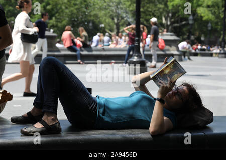 Una giovane donna legge in Washington Square, Greenwich Village, New York. Foto Stock