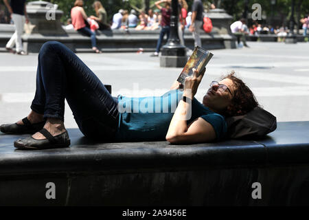 Una giovane donna legge in Washington Square, Greenwich Village, New York. Foto Stock