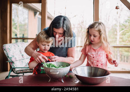 Una nonna insegna nipoti di snap bean verde. Foto Stock